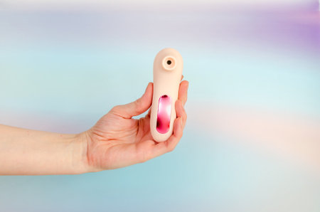 pink vacuum wave vibrator for clitoral stimulation in an elegant female hand. Sex toy for women on a light blue background. A product from a sex shop, for adults. space for textの写真素材