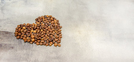 coffee beans are laid out in shape of heart on gray concrete background. space for text. Top viewの写真素材