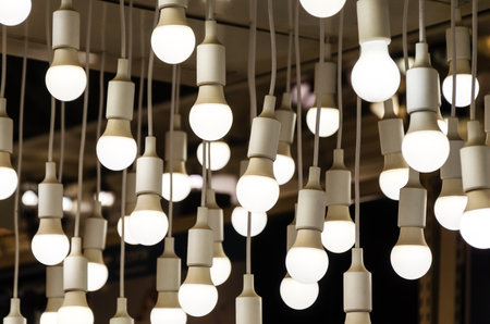Lots of round electric LED lights hang from the ceiling. Original lighting decor of the interior. installation in the form of many light bulbs. lighting equipment storeの写真素材