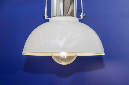 modern chandelier hangs against dark blue wall. Dim lamp light. hanging lamp, decor for room, officeの写真素材
