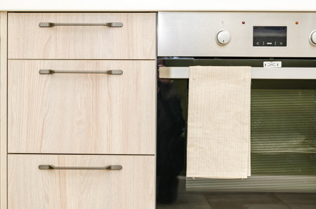 fragment of modern kitchen interior close-up. Wooden facade of kitchen cabinet, glass oven door.の写真素材