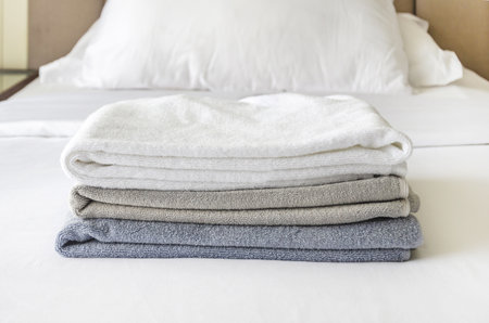 pile of three folded terry towels lies on clean white bed. Cleaning in the guest room of the hotel, cleanliness, laundry. Space for textの写真素材