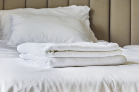 White towels on bed in guest room for hotel customer. folded terry towels lies on clean white bed. Cleaning in the guest room of the hotel, cleanliness, laundry. Space for textの写真素材