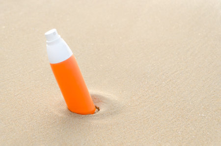 orange bottle sunblock cream on beach. Sun Protection. Sunscreen protection lotion in sand