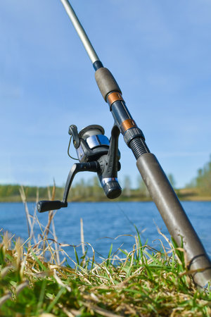 fishing rod with spinning reel. Close-up of fishing tackle. Spinning is installed on the shore of the reservoir. The process of catching fishの写真素材