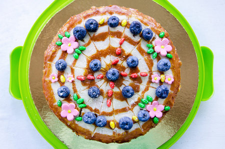 Delicious homemade cake, top view. The cake is decorated with blueberries, flowers and cream. Cute...