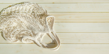 Empty wicker mesh bag on background of wooden tabletop made of sanded planks. White empty string bagの写真素材