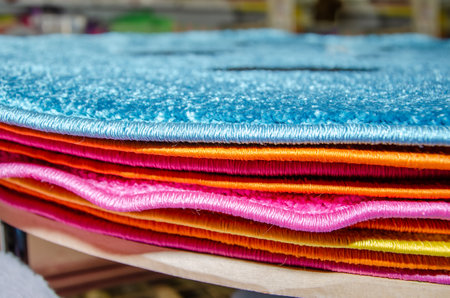 stack of different carpets on counter in the store. Various short woolen rugs, close-upの写真素材