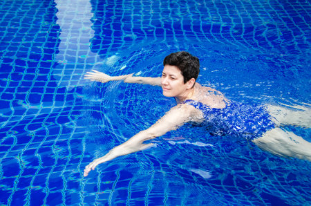 woman swims in the pool. Woman goes in for sports, relaxes in the swimming pool, enjoys.の写真素材