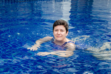 woman swims in the pool. Woman goes in for sports, relaxes in the swimming pool, enjoys.の写真素材