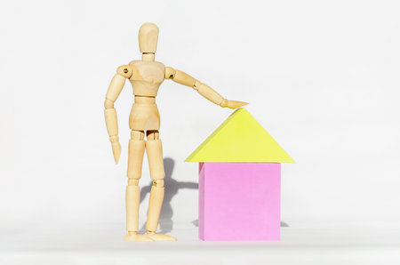 Wooden man next to toy house on white background. concept, mortgage, buying house, security, safetyの写真素材