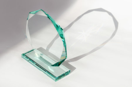 Close-up of a thick cut glass award with highlights and shadows on a white background. Space for text. Glass trophy, template, blankの写真素材