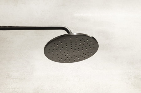 round black shower head in the shower cabin on the background of gray ceramic tiles. shower column...