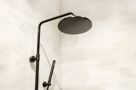 round black shower head in the shower cabin on the background of gray ceramic tiles. shower column with rain shower in the bathroomの写真素材