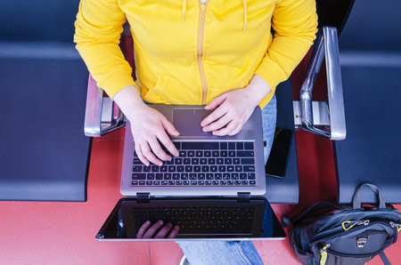 woman works on a laptop, putting it on her lap. Female tourist sitting while waiting for a flight....