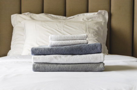 stack of folded terry towels lies on a clean white bed. Cleaning in the guest room of the hotel, cleanliness, laundry, hygiene.の写真素材