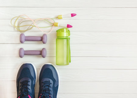 dumbbells, jump rope, water bottle and sports shoes on white wooden background. Fitness backgroundの写真素材