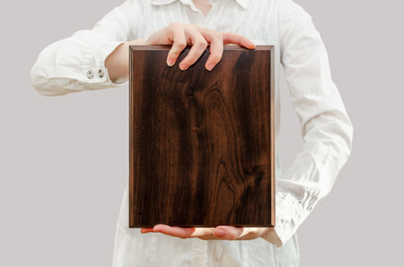 young woman holds wooden award plaque in her hands in front of herの写真素材