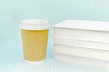 Coffee in paper cup and a stack of books on a light blue checkered backgroundの写真素材