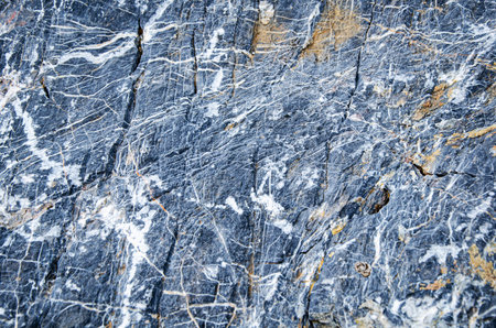 Textured slate rock surface with intricate white veins. The natural geological patterns create a...
