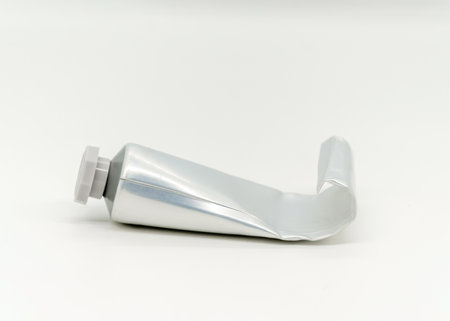 Squeezed plastic tube shown lying on a white surface, displaying its twisted form. The image highlights the tube's empty state and unused potential. Ideal for packaging or recycling concepts.の写真素材