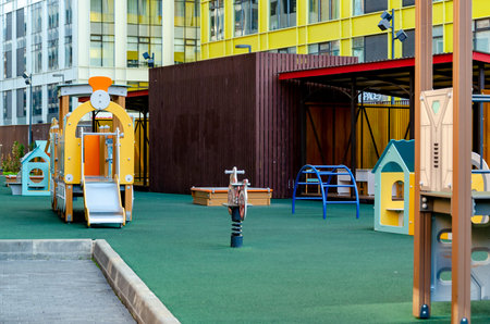 Vibrant playground featuring a slide, climbing structures, and playhouse in an urban setting. Modern...