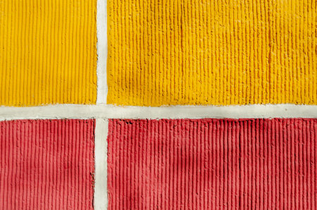 Close-up of a textured surface featuring intersecting yellow and red sections divided by white lines. The bold colors and geometric pattern create a striking visual effectの写真素材