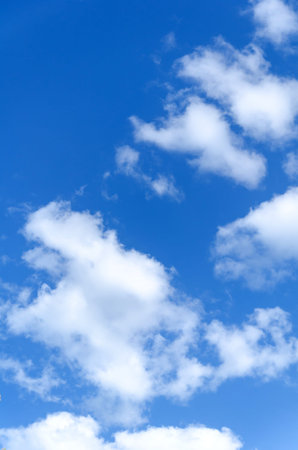 Clear vibrant blue sky, scattered with large, fluffy white cumulus clouds