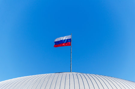 The Russian flag on the dome of the building against a clear blue skyの写真素材