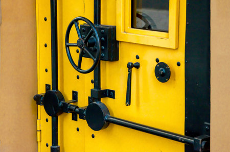 Bright yellow metal door with black bolts and lock hardware, designed to resemble a bank vault.の写真素材