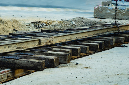 Construction site with removed wooden sleepers and old rails during tramway track renewal. Fresh concrete base, sandy surroundings, overcast sky. Urban infrastructure repair in progress.の写真素材