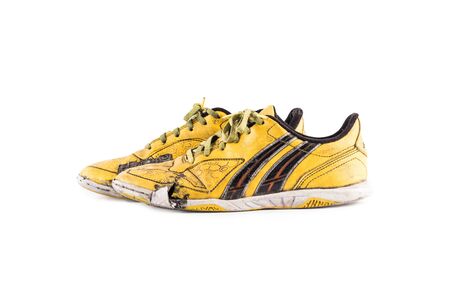 Old  worn out dirty yellow futsal sports shoes  on white background football sportware object isolatedの写真素材