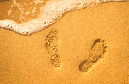 Sunset at a beach with footstep and waveの写真素材