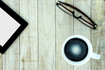 Tablet eyeglasses and a cup of coffee on wood pattern background. Business communication concept.の写真素材