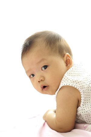 Cute Asian baby lying on the floor. Little Asian infant playing on the floor. Cute baby on white background.の写真素材