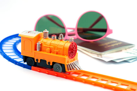 Yellow Train toy on railway and beautiful pink glasses on Thailand passport with Thai cash on white background, travel conceptの写真素材