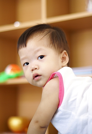Cute Asian Baby in white dress playing in living roomの写真素材