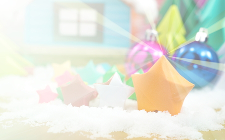 Orange star paper and Christmas ball on snow with the little house in background. Bright field effect in vintage photo.の写真素材