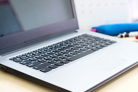 Office workplace with laptop and office supply on wood table,select focus on keyboard.