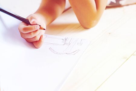 Little kid's hand drawing something on white paper. Outdoor activity learning concept for family. Vintage pastel color style.の写真素材