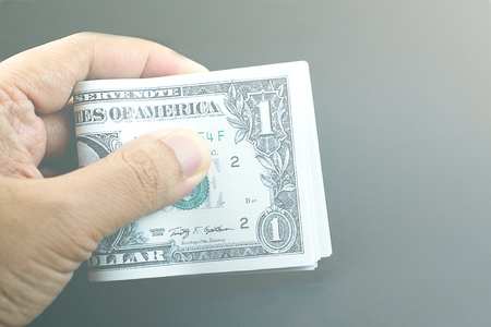 Hand holding US dollar banknote on dark backgroundの写真素材