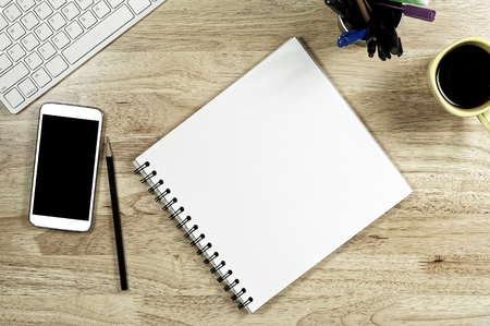 Blank white Paper and smart phone with  black screen and the cup of coffee and office supply for working business communication concept.の写真素材