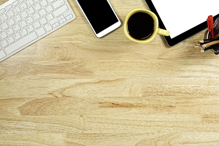 blank screen smartphones and tablet PC on the wooden desktop with computer keyboard and a cup of coffee in composition with copy space for your textの写真素材