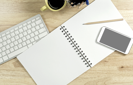 Blank white paper and smart phone with black screen and the cup of coffee and office supply for working business communication concept.の写真素材