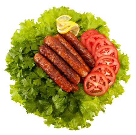 delicious sausages laid on lettuce leaves with tomato slices and parsleyの写真素材