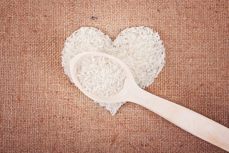 Rice laid out in a heart shape on sackcloth with a wooden spoonの写真素材