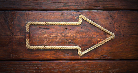 Arrow made of rope on a wooden background
