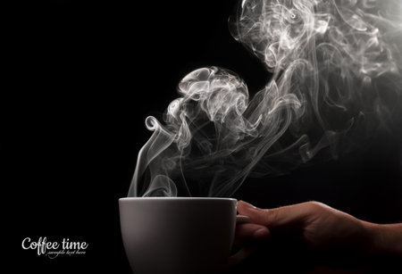 Fragrant coffee on a black background for your advertising. Cup of coffee in his hand. Smoke from hot coffee.の写真素材