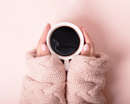 Woman with a cup of fragrant coffee in her hands on a cool day. Black warm coffee in cold weather. View from above.の写真素材