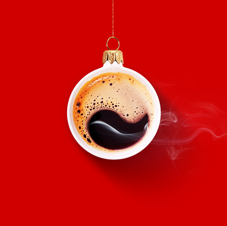 Christmas toy is made from a fragrant cup of coffee. Christmas toy. Holiday concept. Fragrant coffee on a red background for your advertising. Smoke from hot coffee.の写真素材